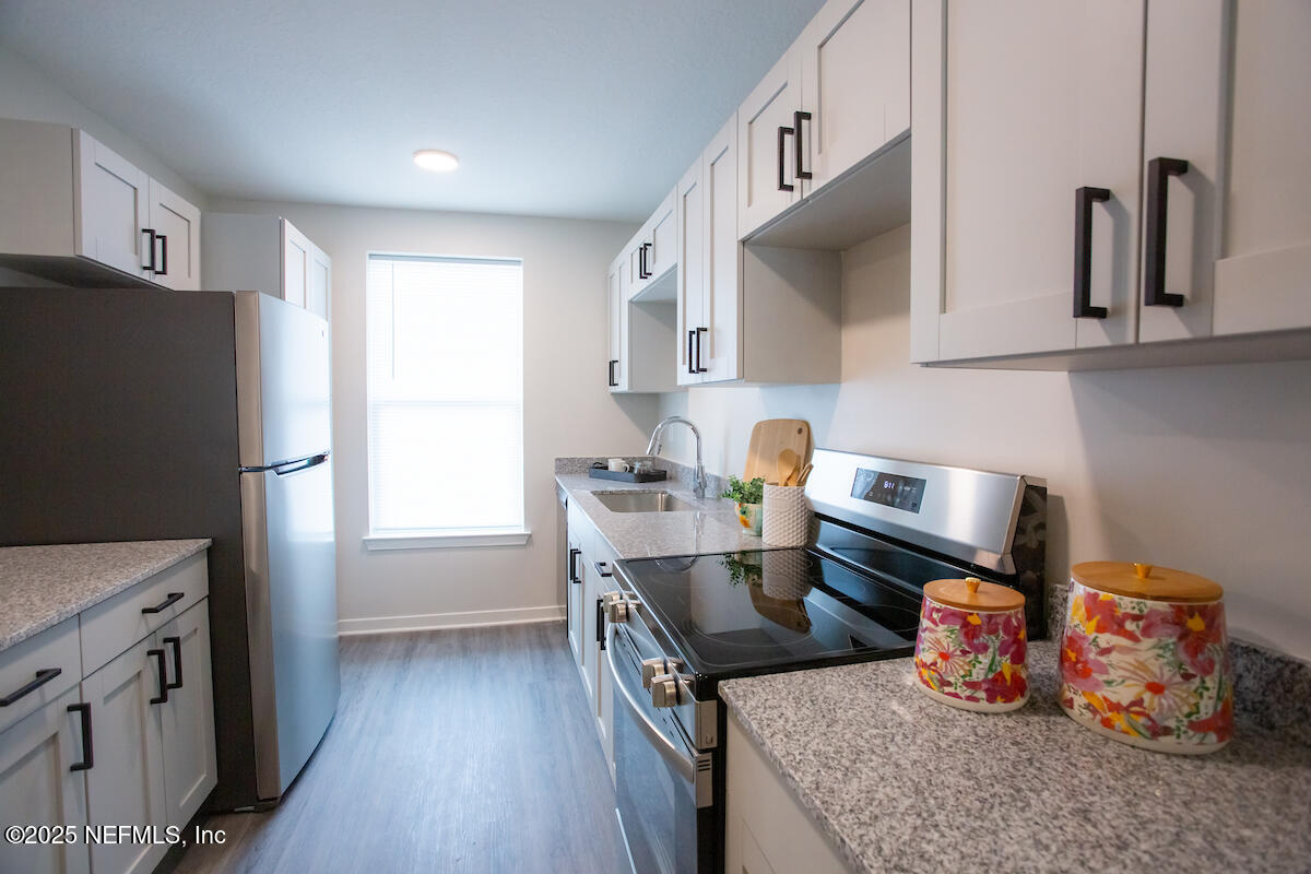 10109 Old St Augustine Road, Unit 1201 Jacksonville, FL 32257 - Photo 5 of 20 a kitchen with stainless steel appliances granite countertop a refrigerator a sink dishwasher a stove and a dining table with wooden floor