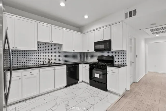 a kitchen with granite countertop white cabinets stainless steel appliances and sink