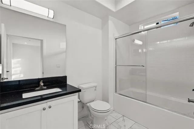 a bathroom with a granite countertop sink a toilet a mirror and shower
