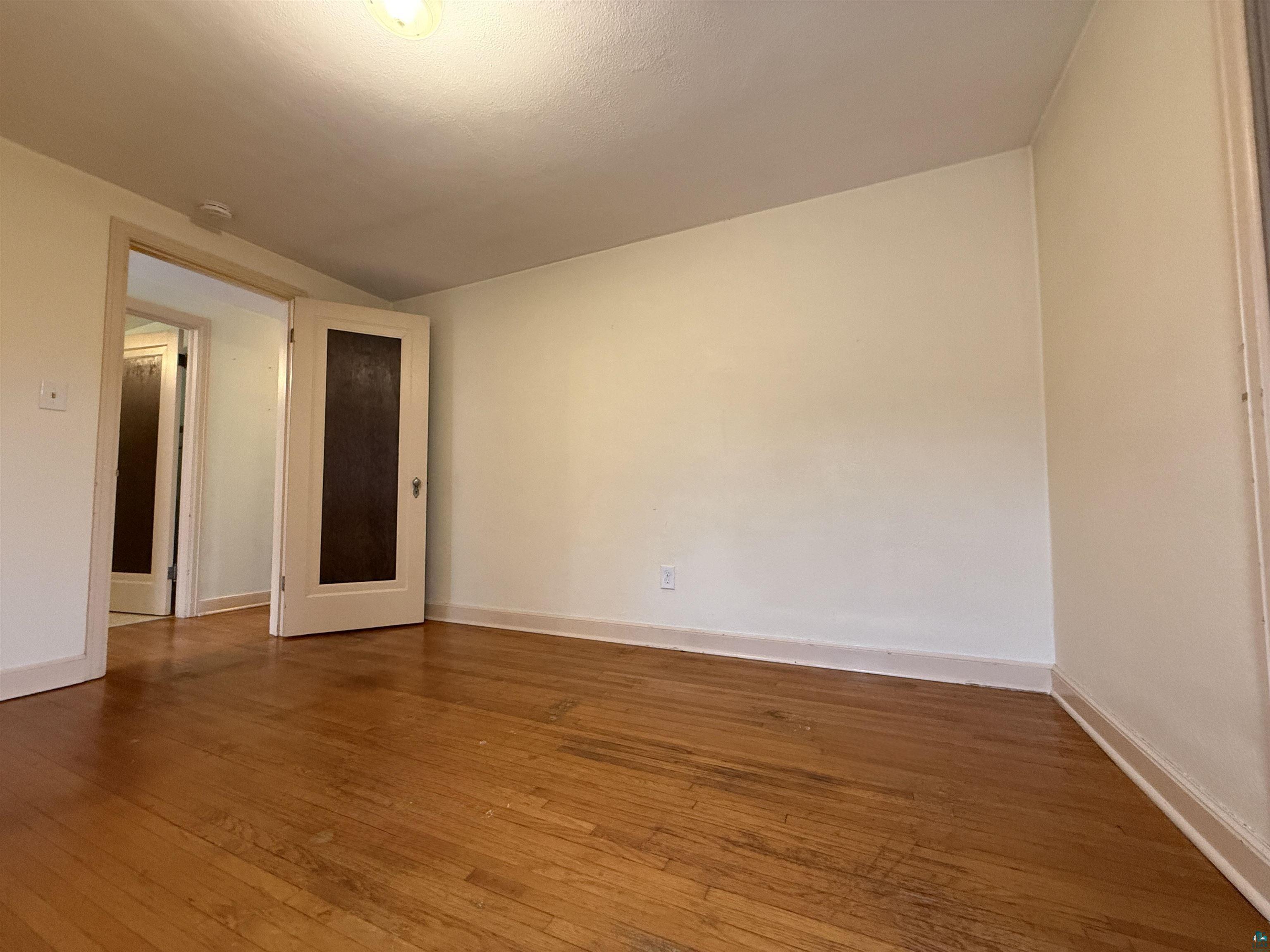 3001 3rd Avenue West Hibbing, MN 55746 - Photo 25 of 38 Spare room featuring dark wood-style flooring and baseboards