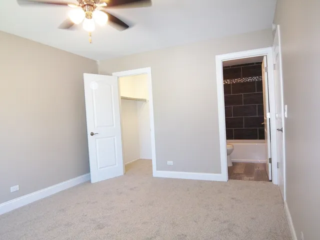 an empty room with closet and a chandelier fan