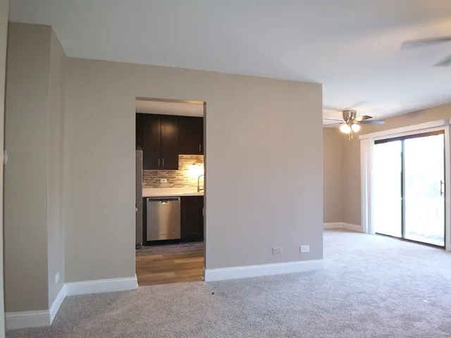 a view of an empty room and a kitchen