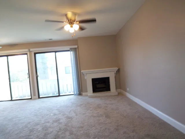 an empty room with chandelier fan and windows