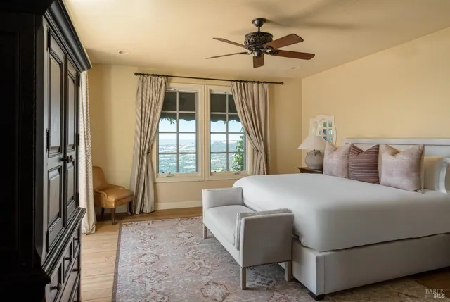 a bedroom with a large bed and a chandelier next to a window