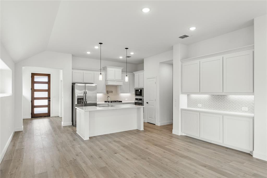 901 Split Oak Lane Anna, TX 75409 - Photo 5 of 31 a kitchen with kitchen island white cabinets and stainless steel appliances