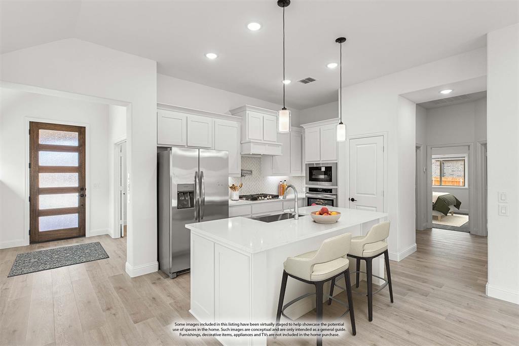 901 Split Oak Lane Anna, TX 75409 - Photo 10 of 31 a dining room with stainless steel appliances kitchen island granite countertop a table chairs and a refrigerator