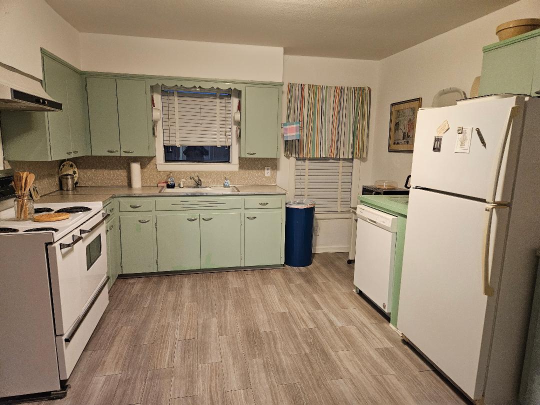 1130 North Main Street Elgin, TX 78621 - Photo 5 of 16 a kitchen with a sink a refrigerator a washer dryer and cabinets