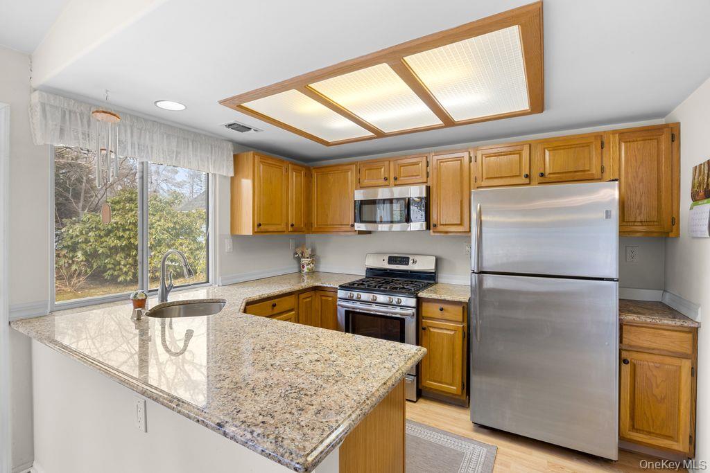 16 Huntington Court Ridge, NY 11961 - Photo 20 of 43 a kitchen with granite countertop a refrigerator a sink a stove and wooden floor