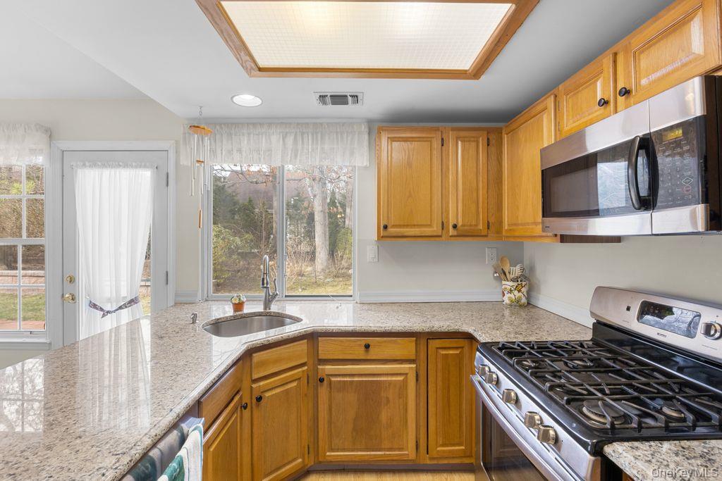 16 Huntington Court Ridge, NY 11961 - Photo 21 of 43 a kitchen with stainless steel appliances granite countertop a stove a sink and a microwave