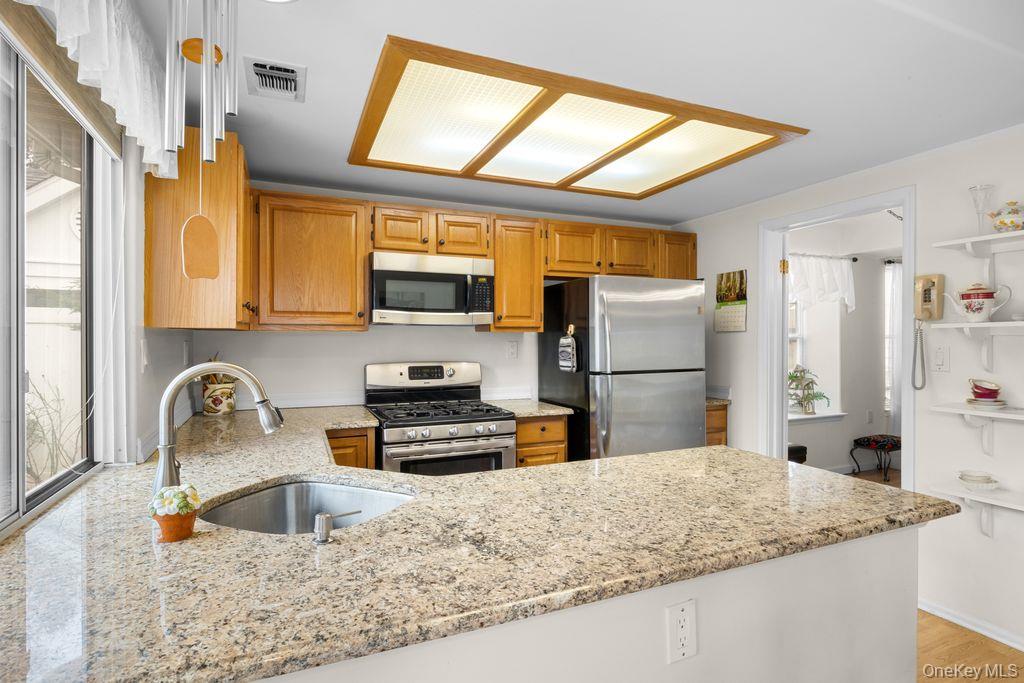 16 Huntington Court Ridge, NY 11961 - Photo 24 of 43 a kitchen with stainless steel appliances granite countertop a sink refrigerator and microwave