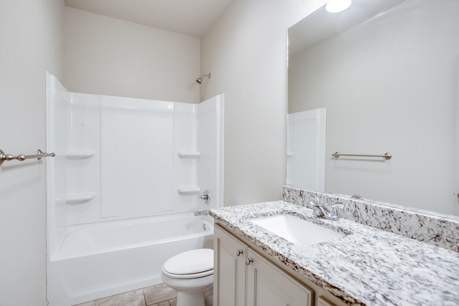 7518 88th Street Lubbock, TX 79424 - Photo 12 of 18 a bathroom with a granite countertop sink a toilet and shower