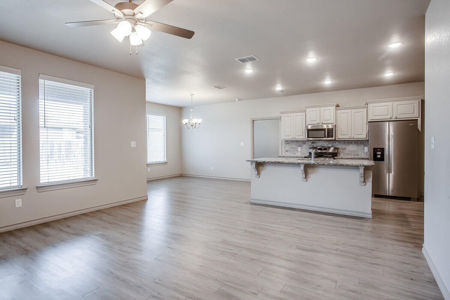 7518 88th Street Lubbock, TX 79424 - Photo 7 of 18 a kitchen with stainless steel appliances kitchen island granite countertop a stove a refrigerator a sink a microwave with wooden floors and cabinets