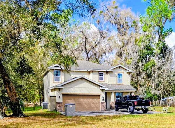 a view of a white house with a big yard and large trees