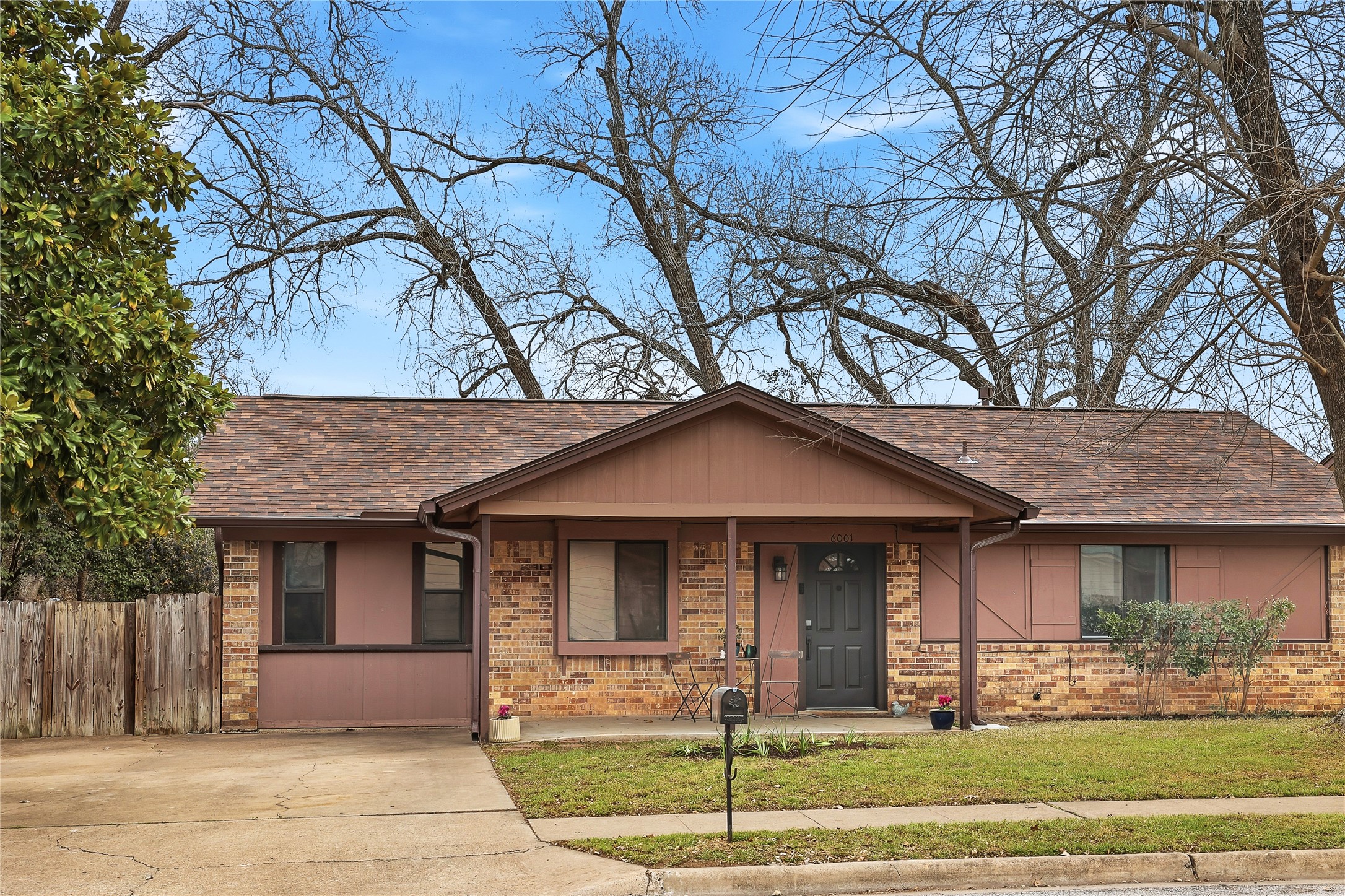 Cozy brick home with a porch, yard, trees with recent roof