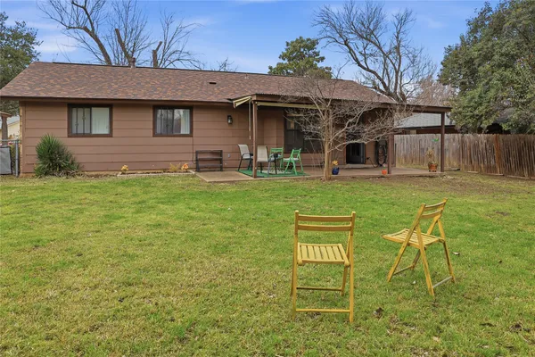 a view of a chair and table in backyard of the house