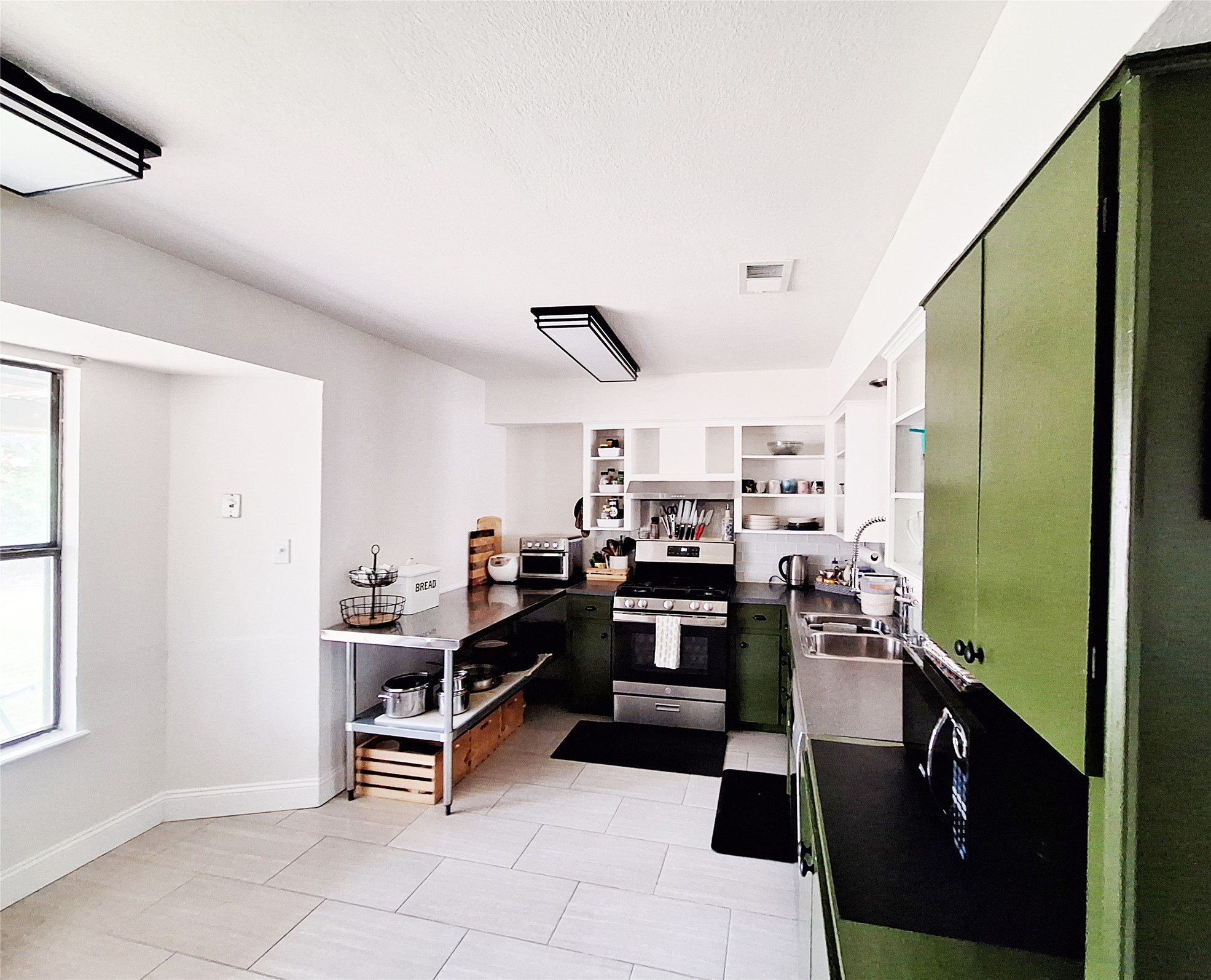6001 Leisure Run Road Austin, TX 78745 - Photo 10 of 24 Kitchen with a window, stainless steel gas range oven, open shelves, and green cabinetry