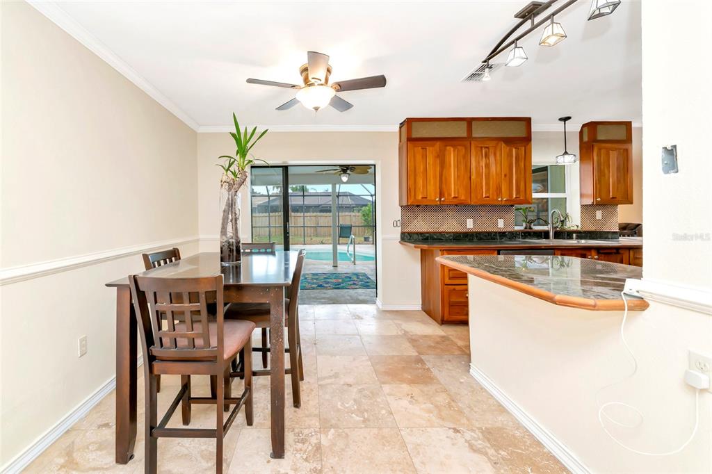 4656 Alexander Pope Lane Sarasota, FL 34241 - Photo 7 of 42 a kitchen with stainless steel appliances granite countertop wooden cabinets a stove a sink a dining table and chairs