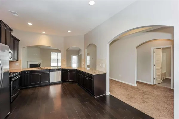 a large kitchen with stainless steel appliances granite countertop a large cabinets a sink and wooden floor