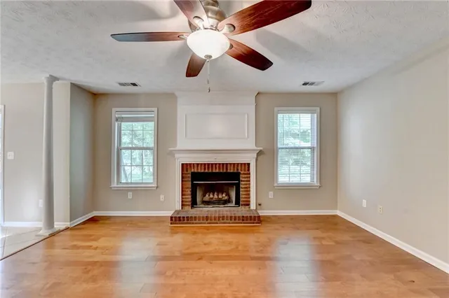 an empty room with windows fireplace and fan