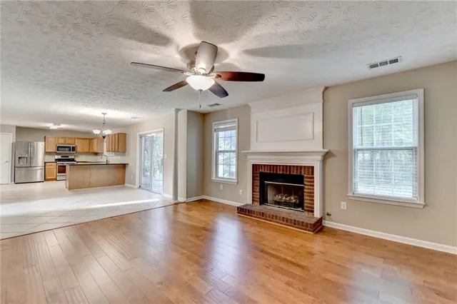 a view of an empty room with wooden floor fireplace and a window