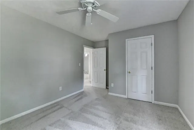 an empty room with a ceiling fan and carpet