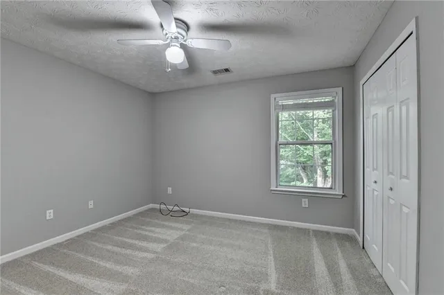 an empty room with windows and fan