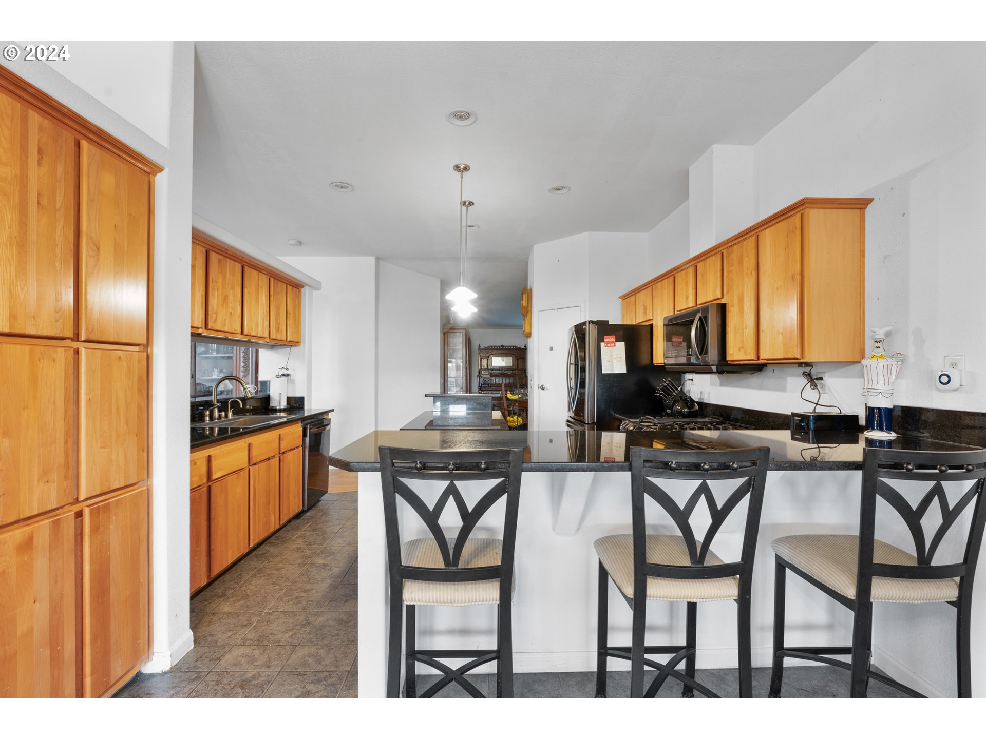 30190 South Oswalt Road Colton, OR 97017 - Photo 17 of 33 a kitchen with stainless steel appliances kitchen island granite countertop a refrigerator a stove a sink dishwasher with a dining table and chairs with wooden floor