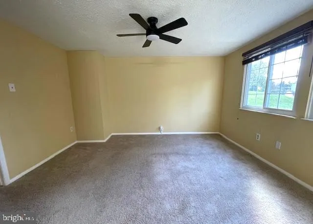 an empty room with a chandelier fan and windows