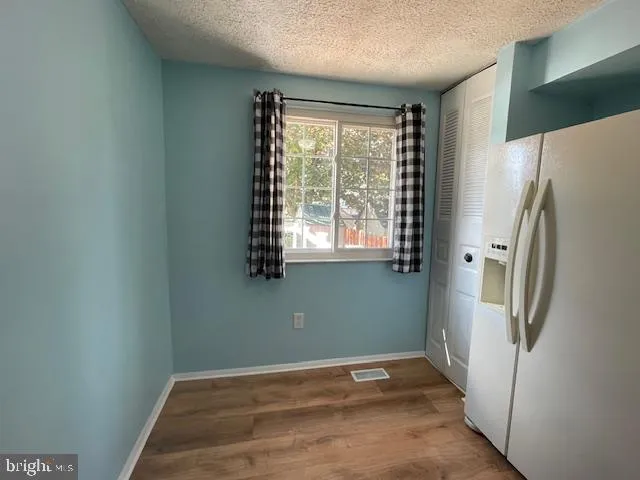 a view of a kitchen with a refrigerator wooden floor and a window