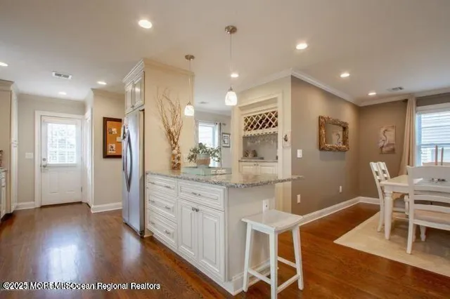 a kitchen with stainless steel appliances granite countertop a refrigerator a sink dishwasher and a stove with wooden floor