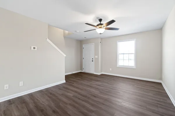 a view of an empty room with wooden floor and a window