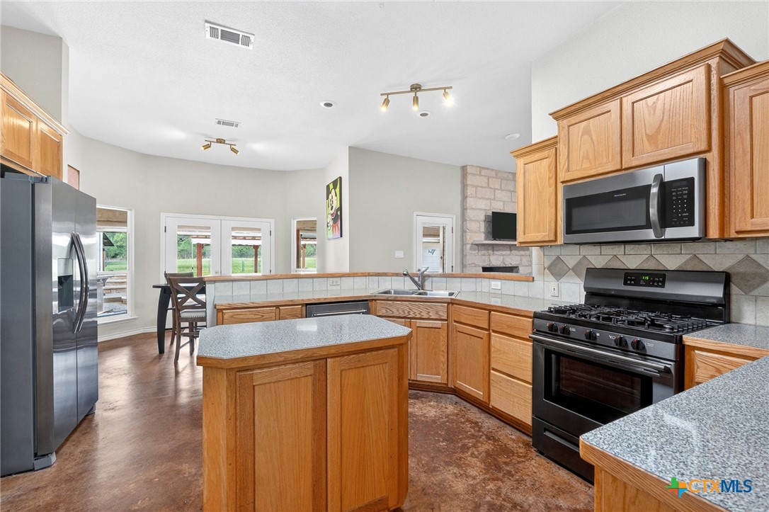 421 Sunset Ridge Drive Killeen, TX 76549 - Photo 22 of 47 a kitchen with stainless steel appliances granite countertop a stove top oven a sink dishwasher a dining table and chairs with wooden floor