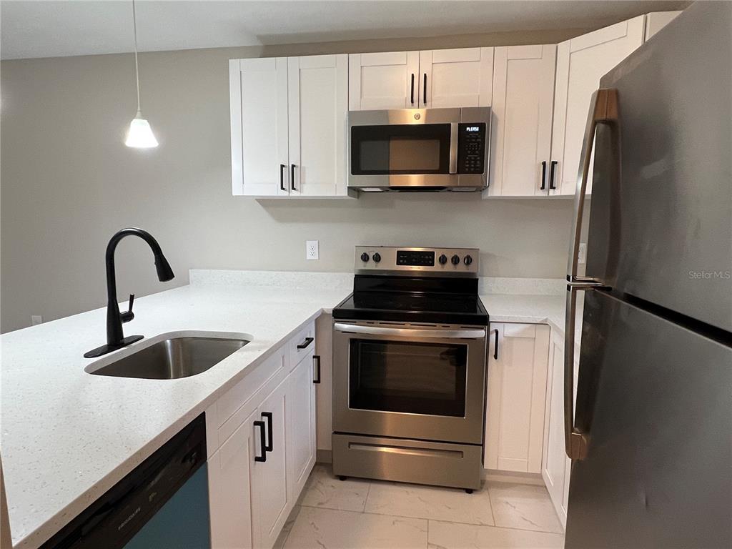 39132 County Road 54, Unit 2064 Zephyrhills, FL 33542 - Photo 3 of 20 a kitchen with white cabinets stainless steel appliances and a sink