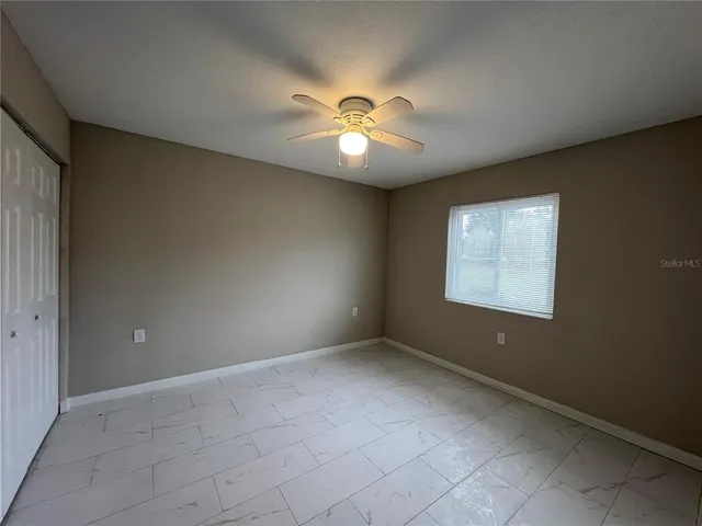 an empty room with windows and fan