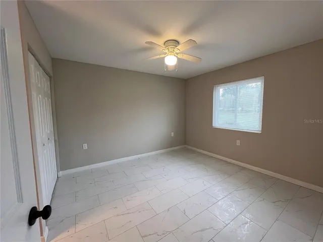 an empty room with closet and a chandelier fan