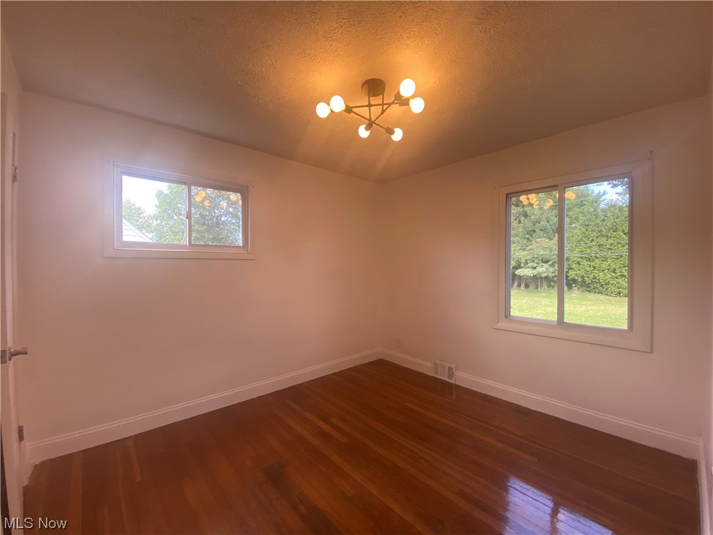 12913 Silver Road Cleveland, OH 44125 - Photo 13 of 23 1st floor bedroom featuring a healthy amount of sunlight and dark hardwood floors
