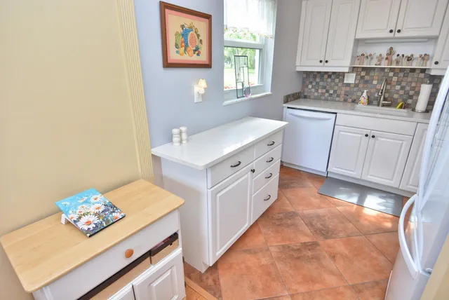 a kitchen with stainless steel appliances a sink a stove a refrigerator cabinets and a window