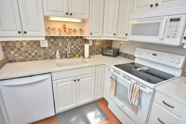 a kitchen with granite countertop white cabinets and white appliances