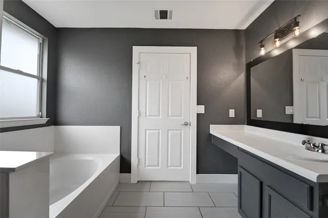 a bathroom with a tub sink and mirror