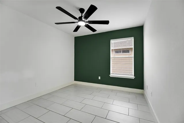 an empty room with a window and ceiling fan