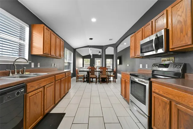 a open kitchen with stainless steel appliances granite countertop a stove top oven a sink dishwasher and cabinets with wooden floor