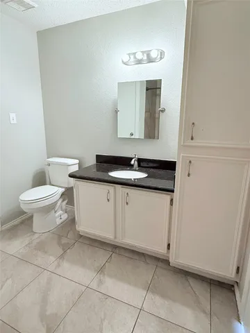 a bathroom with a granite countertop sink a toilet and mirror