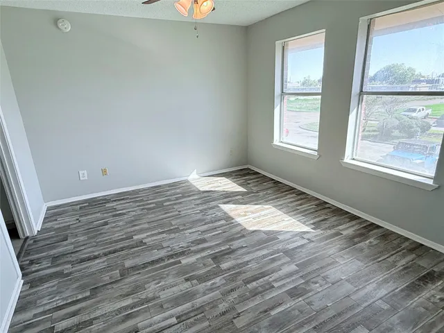 an empty room with wooden floor and windows