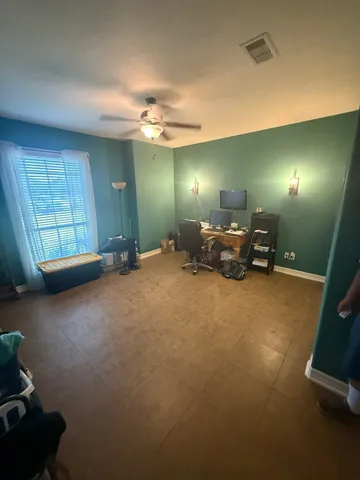 an empty room with windows and fan