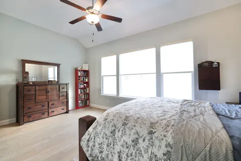 a bedroom with a bed a dresser and a chandelier