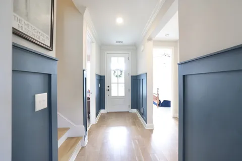 a view of a hallway with wooden floor and a bathroom