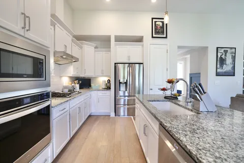a kitchen with stainless steel appliances granite countertop a sink stove and refrigerator