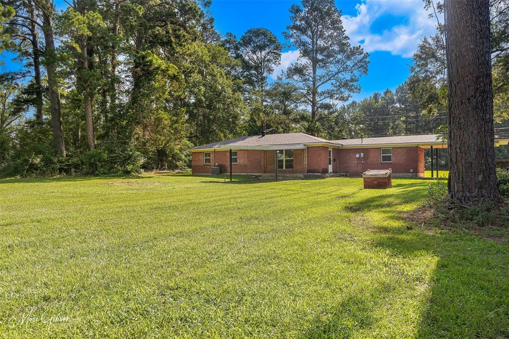 9342 Dean Road Shreveport, LA 71118 - Photo 2 of 18 Expansive lawn area featuring a brick exterior structure and surrounding mature trees