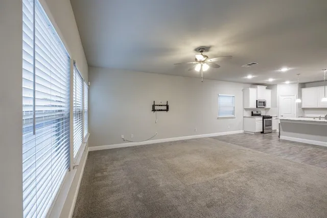 an empty room with chandelier fan and windows