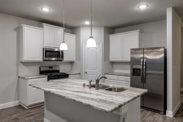 a large kitchen with stainless steel appliances granite countertop a stove a sink and a refrigerator